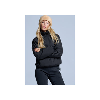 Blonde vrouw draagt zwarte halfzip sweater en beige muts, armen over elkaar, casual sportieve look