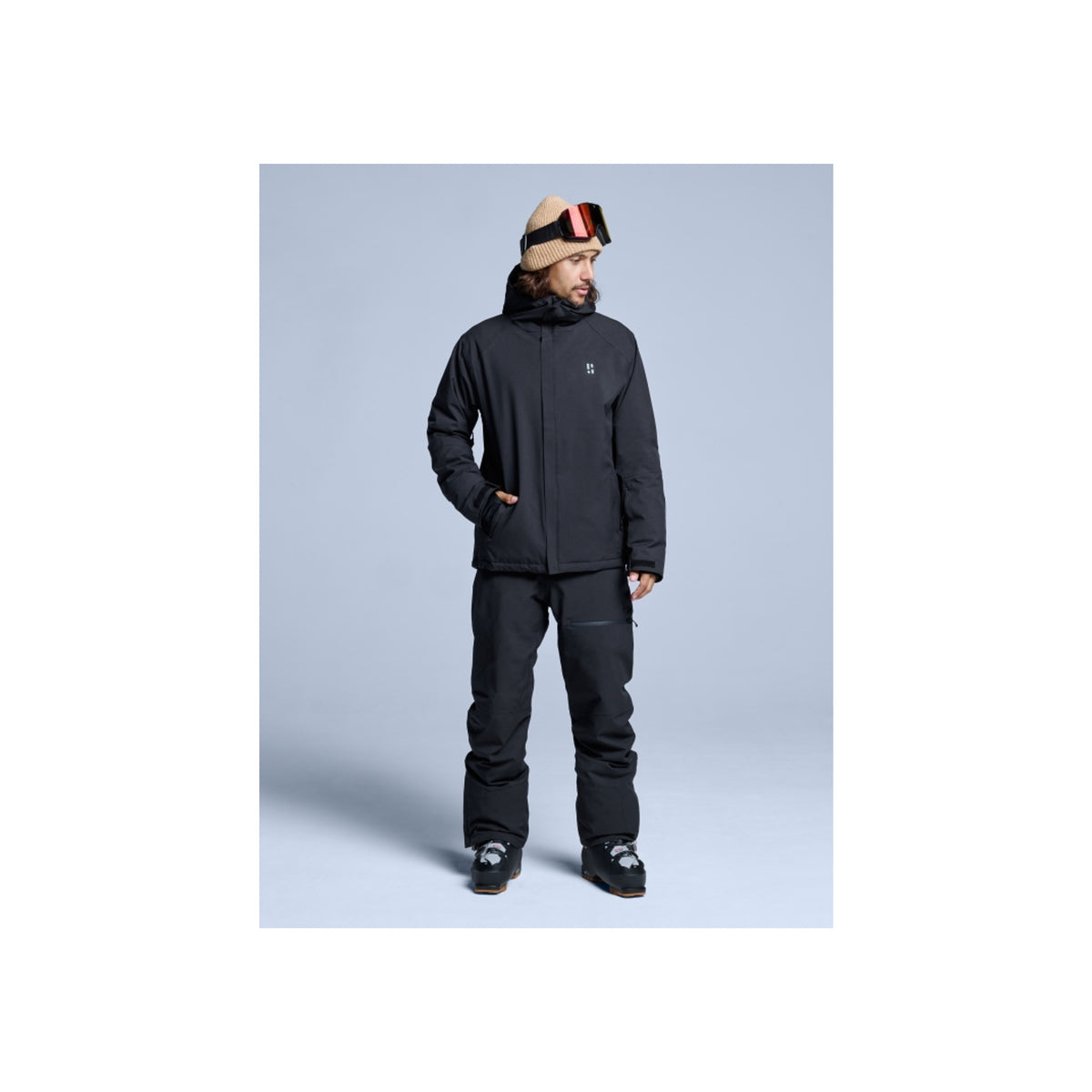Man in zwarte ski-jas en broek met skibril op hoofd, complete wintersport outfit voor heren