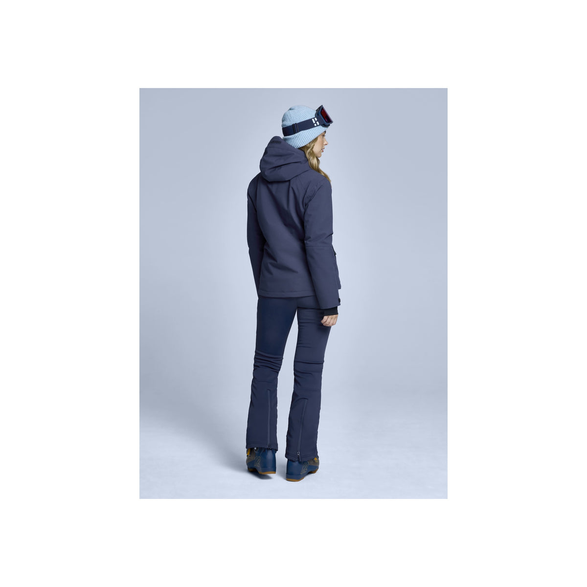 Vrouw in marineblauwe ski-jas en broek, achterkant - wintersportkleding dames