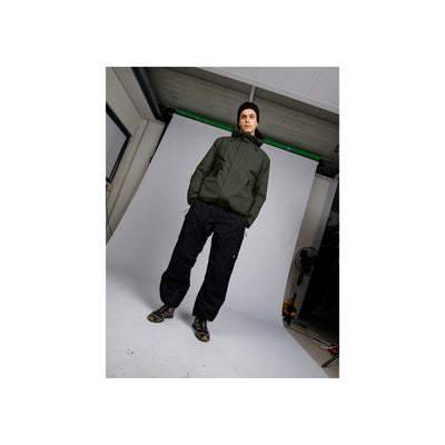 Model draagt groene hoodie en zwarte joggingbroek met sportschoenen in urban setting