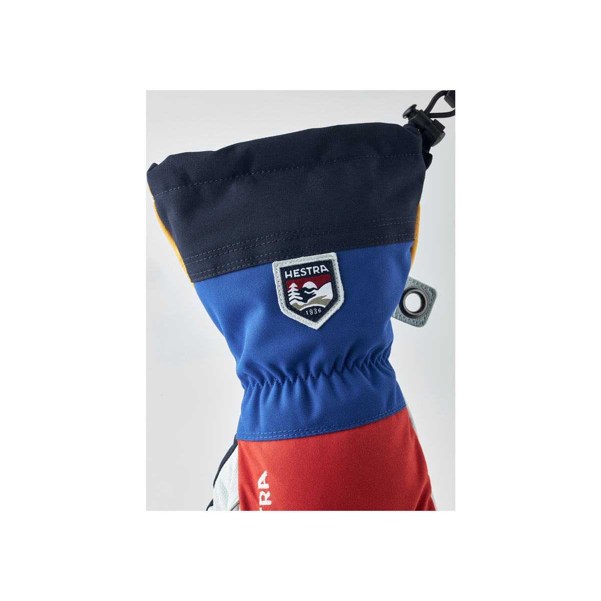 Hestra ski handschoen detail met logo, blauw en rood kleurblok design met elastische pols