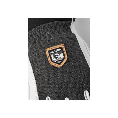 Hestra logo badge op donkergrijze skihandschoen met beigerand en Est. 1936 opschrift
