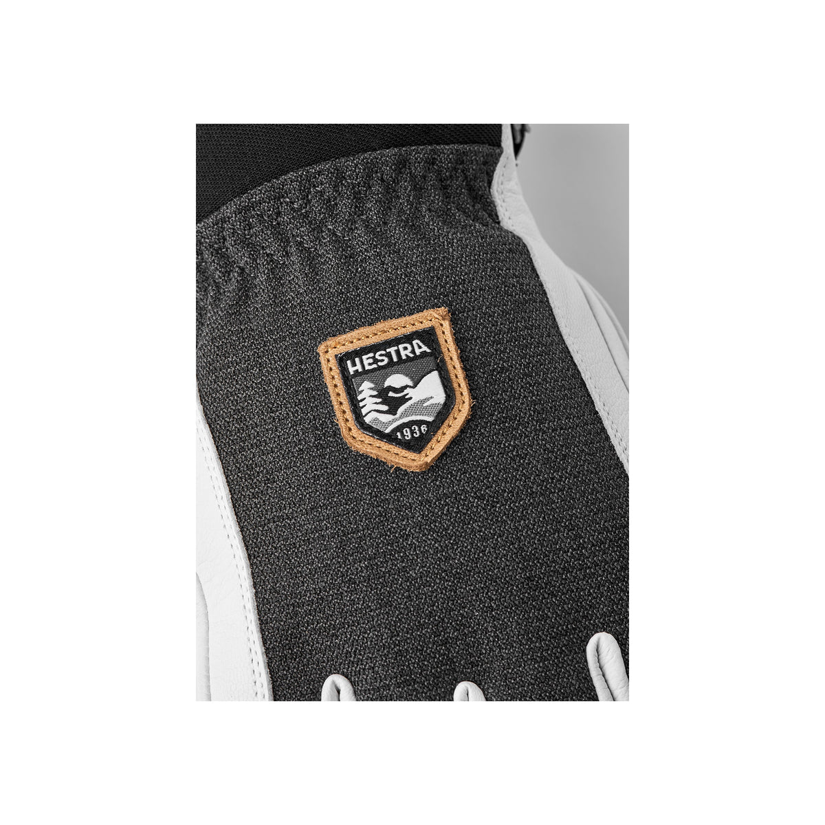 Hestra logo badge op donkergrijze skihandschoen met beigerand en Est. 1936 opschrift