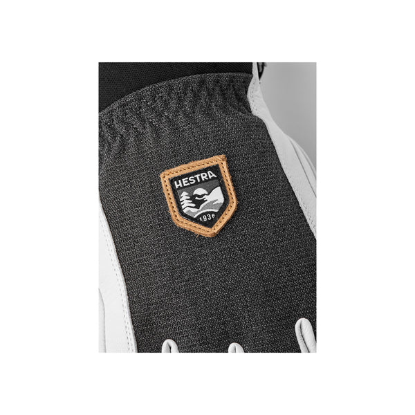 Hestra logo badge op donkergrijze skihandschoen met beigerand en Est. 1936 opschrift