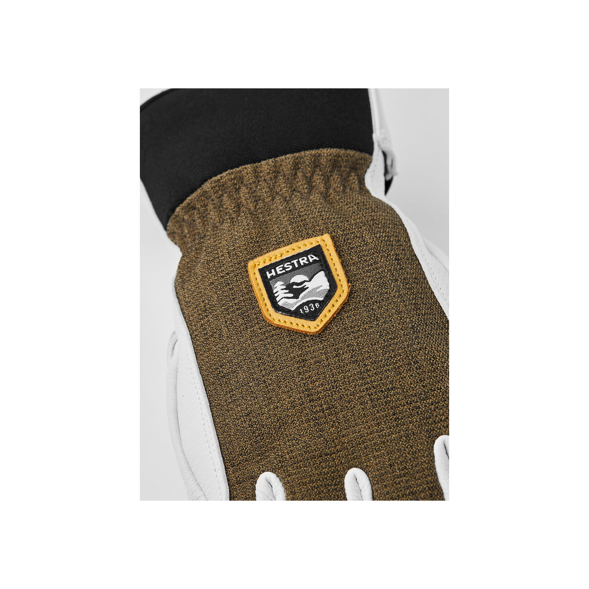 Hestra handschoen met bruin gebreid manchet en geborduurd logopatch op witte achtergrond