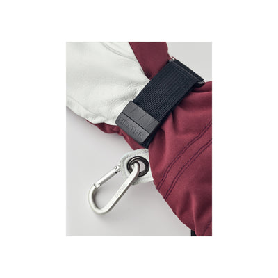 Detail van bordeauxrode jas met zwarte velcro sluiting en metalen karabijnhaak
