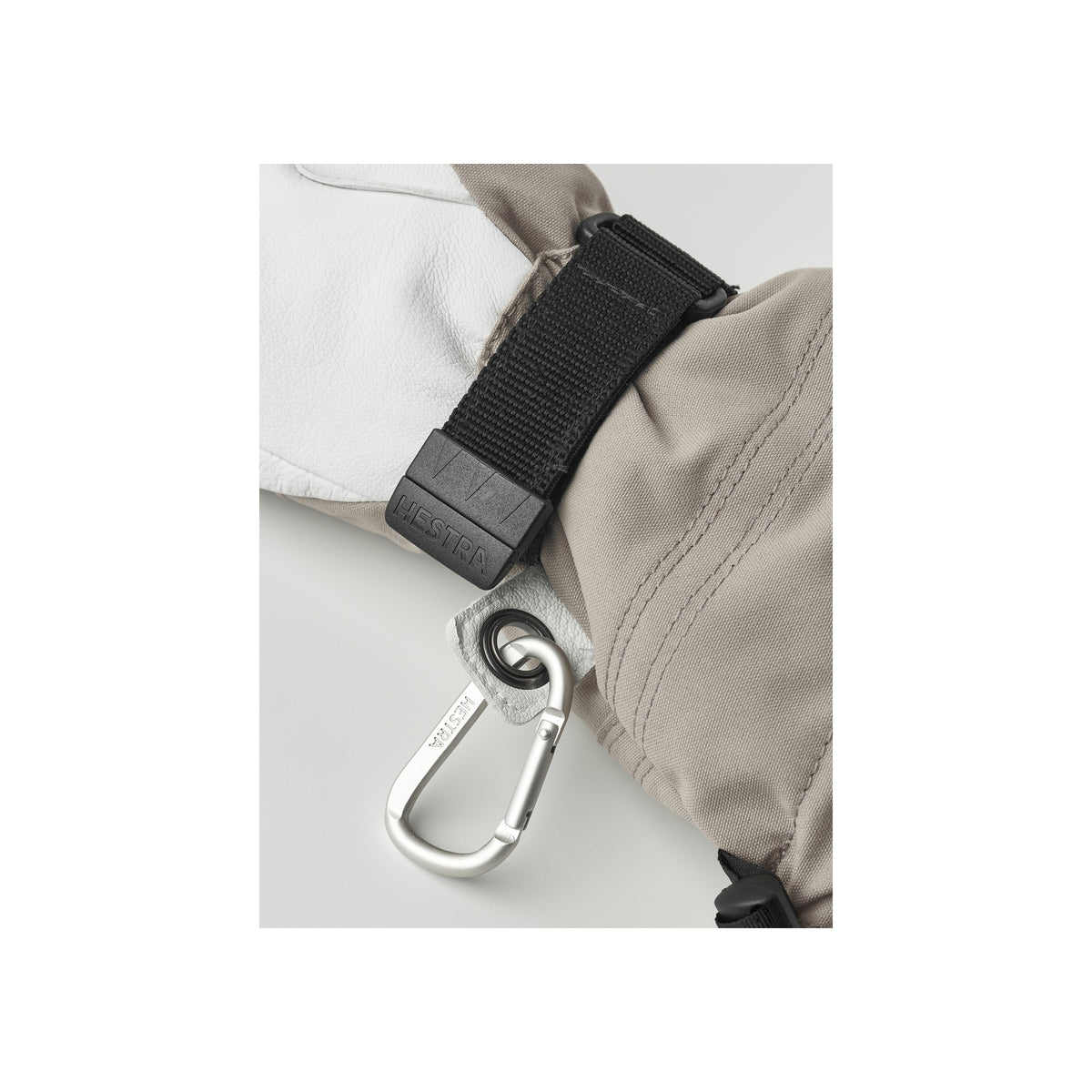 Detail van beige tas met zwarte clipband en metalen karabijnhaak