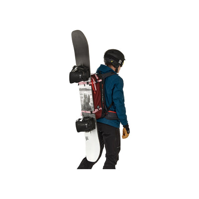 Snowboarder met skischoenhouder en snowboard op rug, zijaanzicht tegen witte achtergrond
