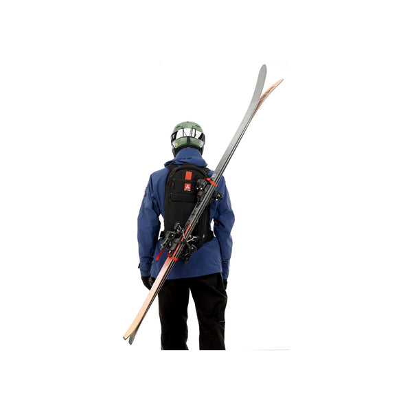 Achterkant van skiër met ski's op rugzak, helm en blauwe jas - wintersport uitrusting