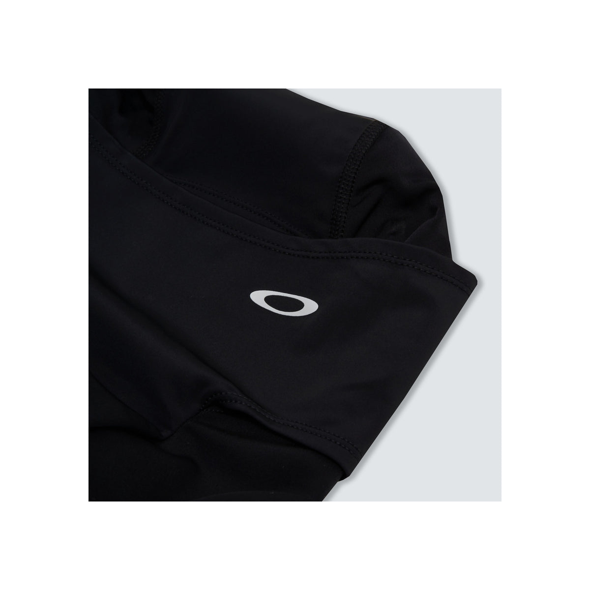 Zwart Oakley shirt met wit logo detail op de borst, close-up van premium sportkleding