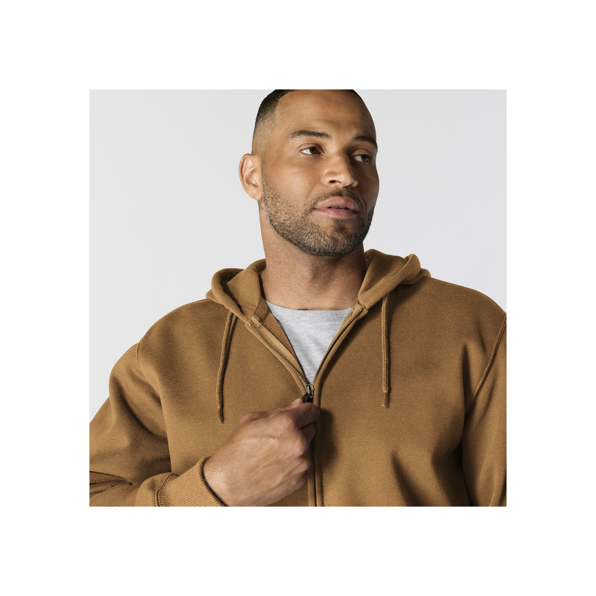 Man draagt bruine hoodie met rits en capuchon, casual streetwear stijl