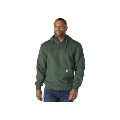Man draagt groene hoodie met halve rits en kangoeroe zak, gekleed in spijkerbroek