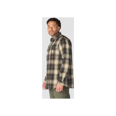 Man draagt oversized geruit flannellen overhemd in bruin en beige tinten met groene broek op lichte achtergrond