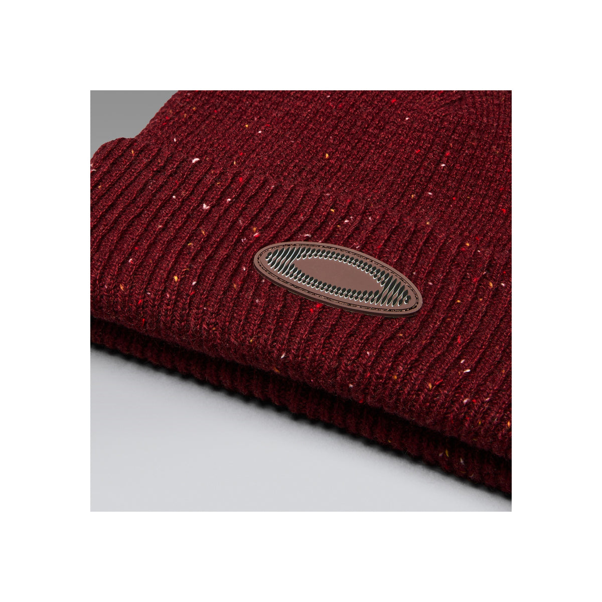 Bordeauxrode gebreide wintermuts met metalen logo badge en gevlekte textuur