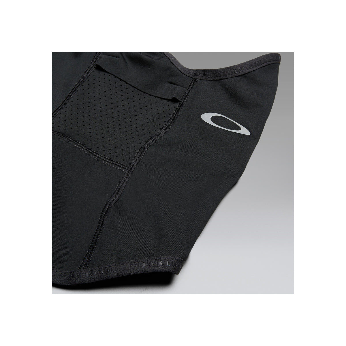 Zwarte sportbeha met geperforeerd paneel en Oakley logo detail, close-up van premium materiaal