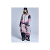 Vrouw in roze-grijs-zwart ski-onesie met capuchon en winterlaarzen op lichte achtergrond