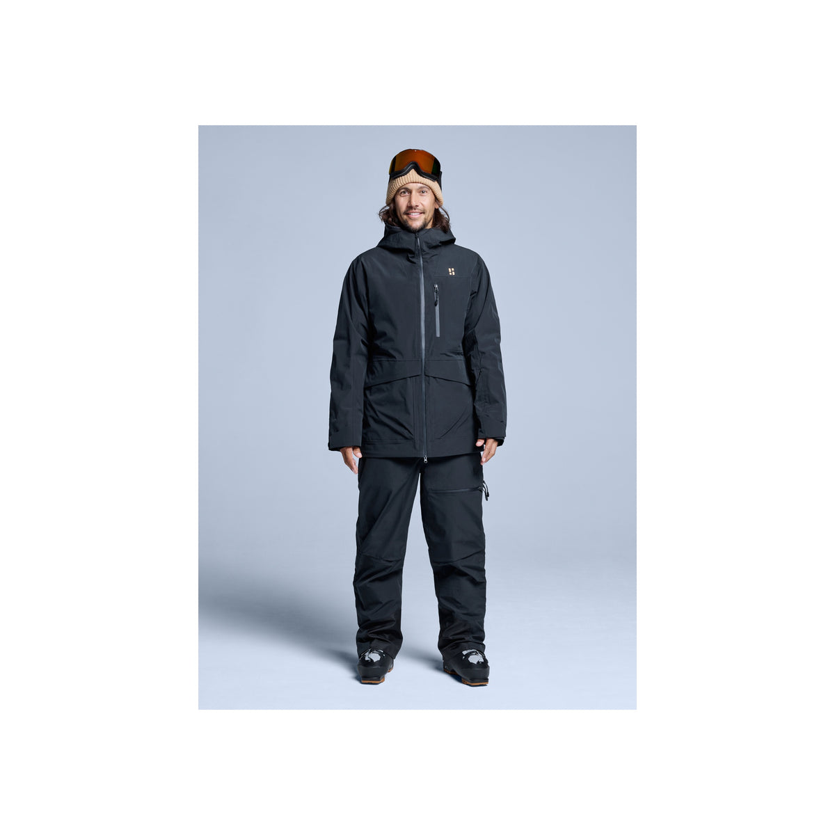 Man draagt Poederbaas Freeride 3L Shell Jacket in donkerblauw met skibroek en muts - winterjas voor heren