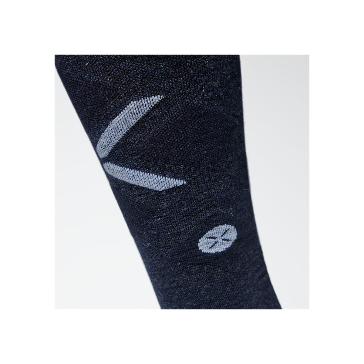 Close-up van donkerblauwe compressiesok met lichtblauw logo op de kuit