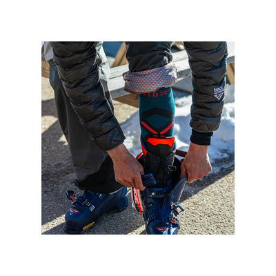 Persoon maakt skischoenen vast, close-up van blauwe ski boots met rode details en zwarte winterkleding