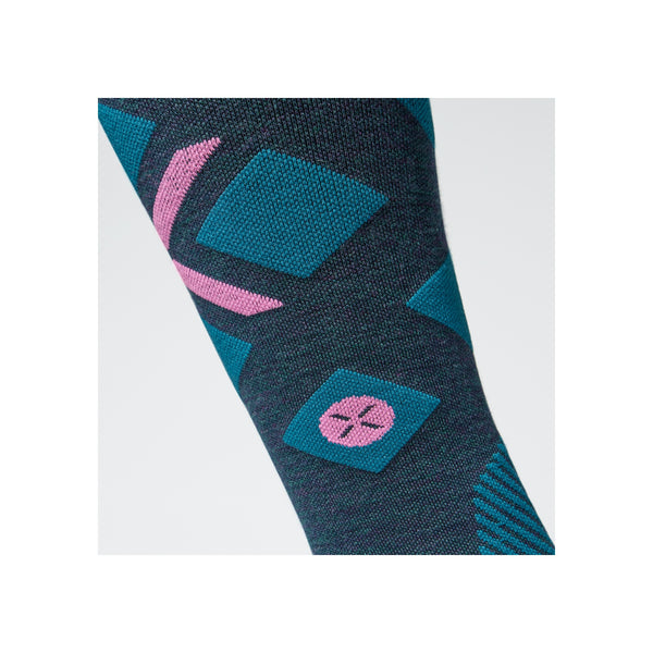 Grijze compressiesok met blauw en roze geometrisch patroon, close-up van enkel en onderbeen